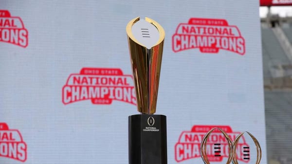 College Football Playoff logo on the field with players lined up for kickoff